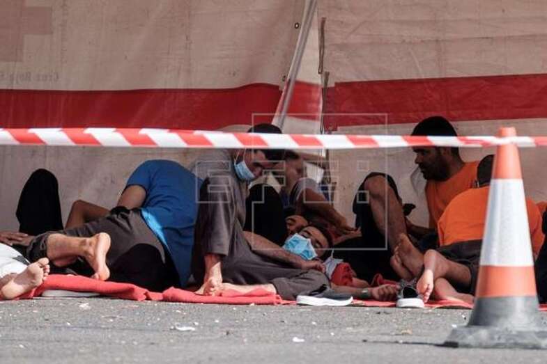 Un grupo de inmigrantes espera bajo unas carpas de Cruz Roja en el puerto de Arguineguín (Foto EFE / Ángel Medina G.)
